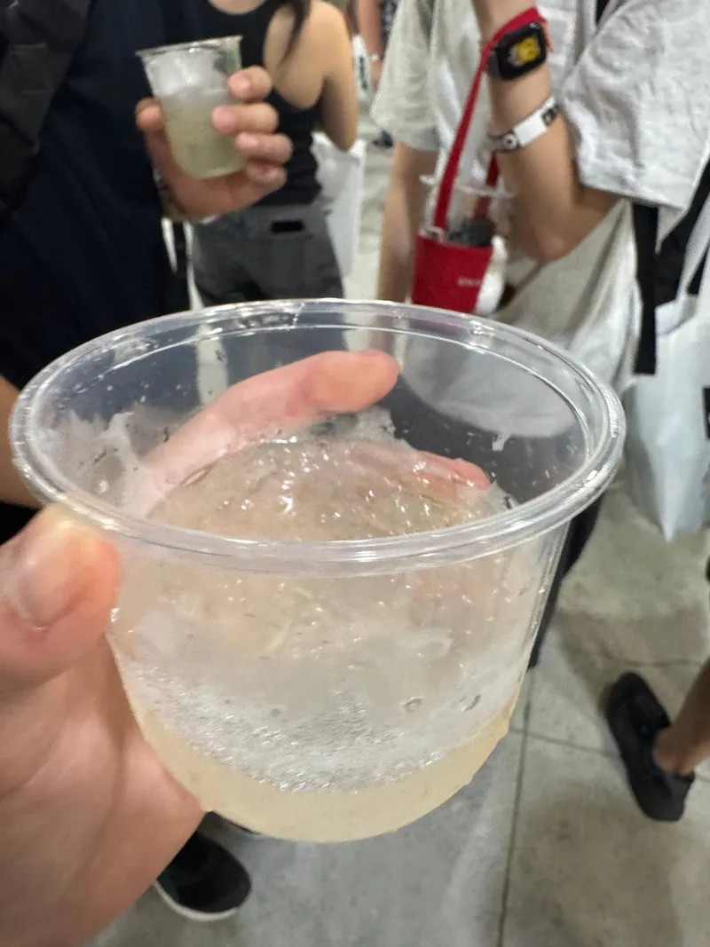 手持透明杯中的淡色琴酒調酒，酒液表面帶著細緻泡沫