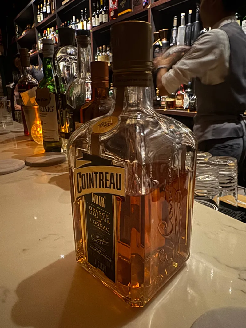 吧台上的 Cointreau Noir 君度酒瓶，標籤標示橙酒與干邑